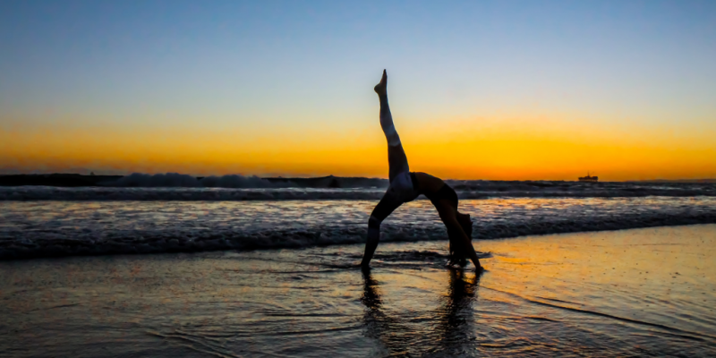 Woman doing yoga on a beach at sunset